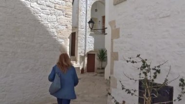İtalya, bölge, Locorotondo, tarihi merkezi Ortaçağ kökenli dar sokaklarında oluşan ve dar sokaklar, badanalı evler ve çiçeklerle Puglia. Turist ziyaret etti. Zaman atlamalı