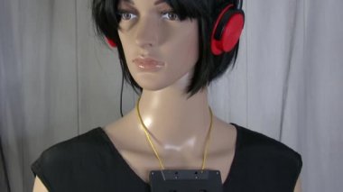 Moda videosu için ön planda stereo kulaklıklı bir kadın manken poz veriyor. 4K 50 fps