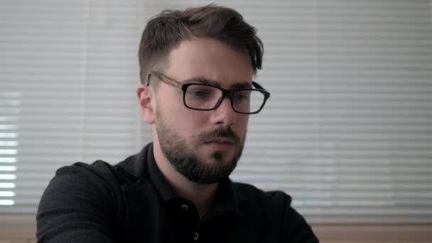 Primo piano di giovane uomo di successo che lavora su laptop con statistiche in occhiali — Video Stock