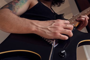 Kapalı mekanda siyah ve sarı elektro gitar çalan bir erkeğin alt görüntüsü. Rock ve müzik konsepti