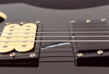 Altı tane siyah elektro gitar teli, ahşap pano ve mikrofona yakın çekim. Aletler ve müzik konsepti