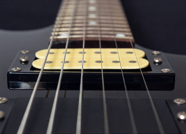 Closeup to a six electric guitar strings, wooden fretboard and microphones . Instruments and music concept