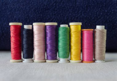 Beyaz tekstil ve koyu mavi arkaplan üzerine sekiz renkli dikiş ipliği. moda ve tekstil kavramı