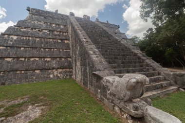Rahip mezarı olarak bilinen antik Maya piramit yapısının güzel bir görüntüsü ya da yontulmuş bir yılan başı ve Chichen Itza arkeoloji sahasına çıkan merdivenli ossuari.