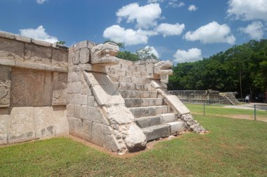 Güneşli bir günde Chichen Itza arkeoloji sahasına oyulmuş yılan başları ve merdivenleri olan antik bir Maya platformunun detayları.