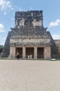 Jaguar Tapınağı olarak bilinen antik Maya tapınağının önünden Chichen Itza arkeolojik alanına doğru yürüyen genç bir kadın görülüyor.