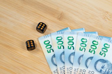 Bir çift siyah zara yakın, altılı ve Meksika 500 pezosu olan ahşap bir arka planda.