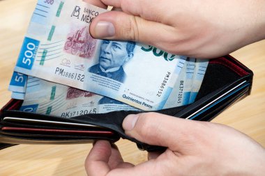 Meksika 'lı bir erkeğin 500 peso' luk bir cüzdanı ahşap arka planda çıkarmasına yakın.