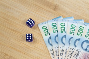 Bir çift mavi zarın yanına iki tane altılı, Meksika 500 pesosu da ahşap bir arka planda.