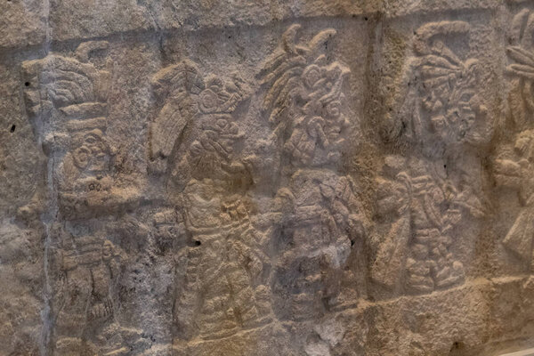 Рядом с древним резным камнем майя, представляющим воинов в музее Канкун Майя.