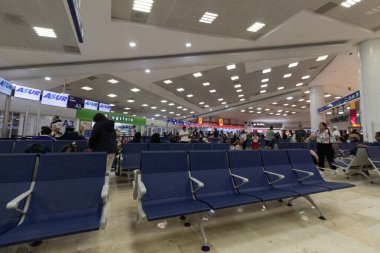 Cancun Havaalanı uluslararası pansiyon. Arka planda yolcuları ve hediyelik eşya dükkanları olan mavi sandalyeler.