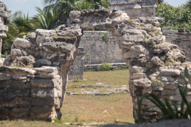 Tulum arkeolojik bölgesinin taş kavis girişinden görülen antik Maya harabelerinin güzel bir görüntüsü.