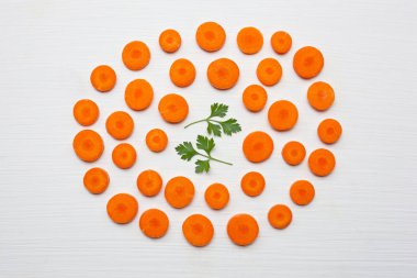 Doğranmış havuç dilimleri ve maydanoz yaprakları beyaz arka plan üzerinde izole.