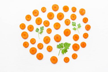 Doğranmış havuç dilimleri ve maydanoz yaprakları beyaz arka plan üzerinde izole.