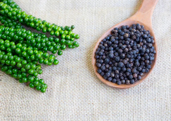 Fresh green peppercorns with black peppercorns