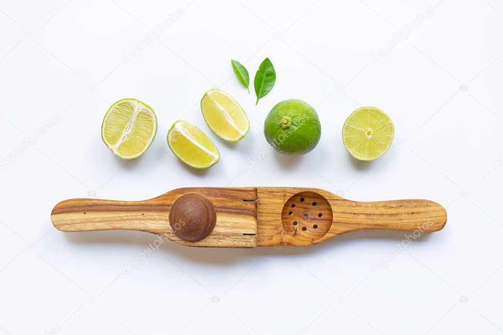 Limes  with wooden lime Squeezer on white background.