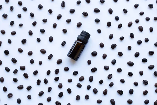 Glass bottle with essential oil of coffee and Coffee grains on white background