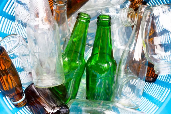 Glass bottles in blue waste basket.