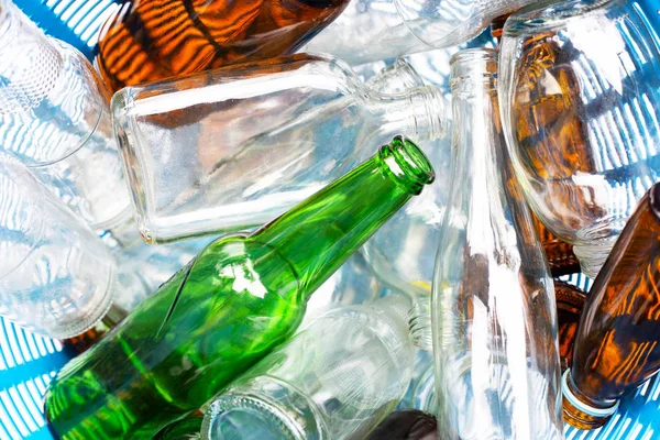 Glass bottles in blue waste basket.