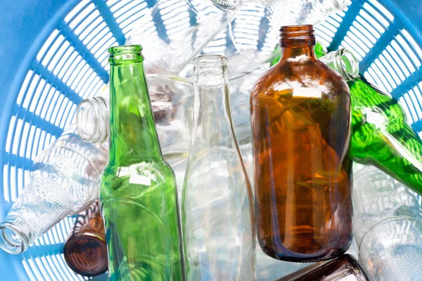 Glass bottles in blue waste basket.