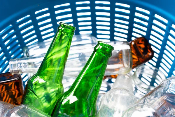 Glass bottles in blue waste basket.