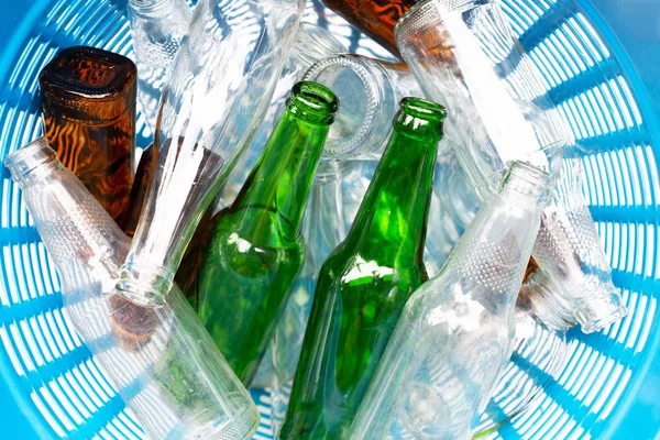 Glass bottles in blue waste basket.