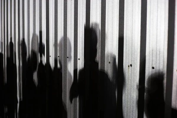 People shadow on zinc wall background.