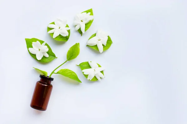 Garrafa de óleo essencial com flor de jasmim e folhas em branco . — Fotografia de Stock