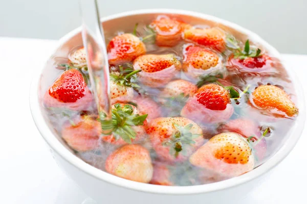 Strawberries soaked in water. Washing fresh fruit. on white. — Stock Photo, Image
