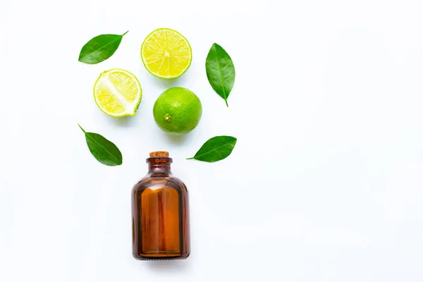 Ripe limes with essetial oil on white — Stock Photo, Image