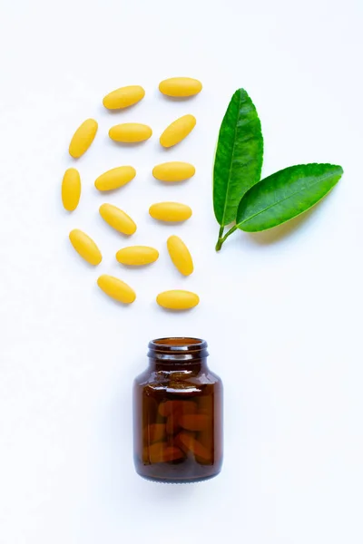 Bouteille de vitamine C et pilules avec des feuilles vertes sur blanc — Photo