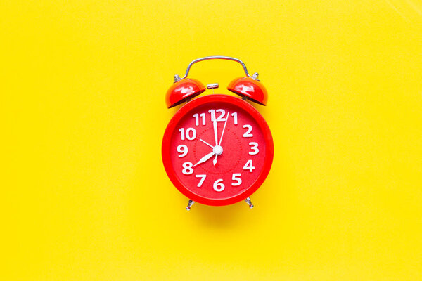 Red alarm clock ring on yellow background. 