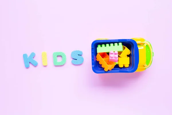 Brinquedos coloridos para crianças com alfabeto "KIDS" no fundo rosa . — Fotografia de Stock