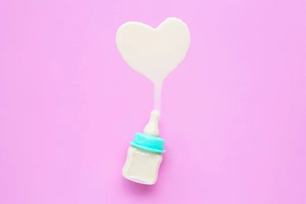 Бутылка молока для малыша на розовом фоне. Форма молочного сердца . — стоковое фото