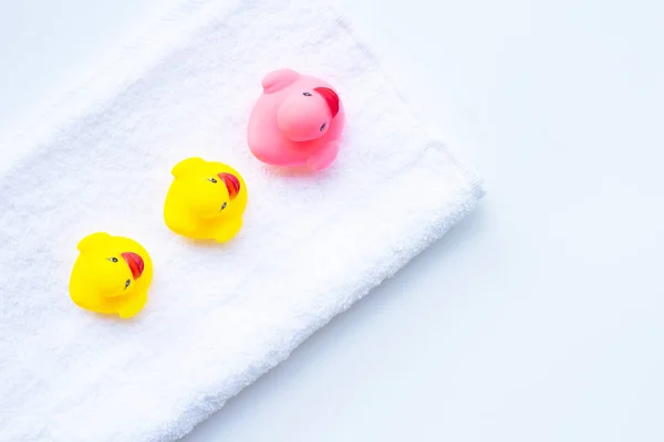 Juguetes de pato rosa y amarillo en toalla blanca. concepto de baño para niños . — Foto de Stock