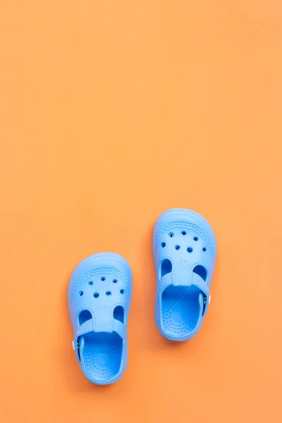 Синие детские резиновые сандалии на оранжевом фоне . — стоковое фото