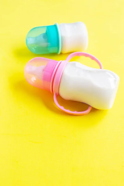Milchflaschen für Baby auf gelbem Hintergrund. — Stockfoto