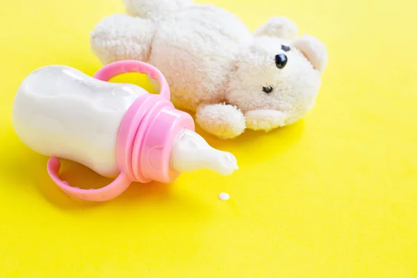 Flasche Milch für Baby mit Spielzeug weißer Bär auf gelbem Hintergrund — Stockfoto
