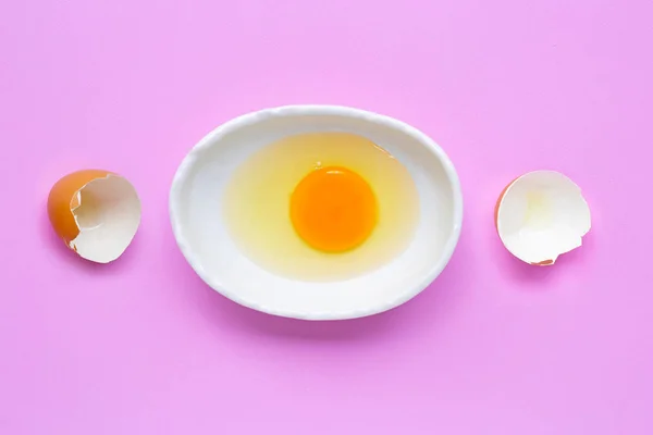 Gema de ovo e branco em uma tigela no fundo rosa . — Fotografia de Stock
