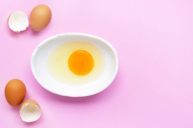 Yumurta sarısı ve beyaz pembe arka plan üzerinde bir kapta. 