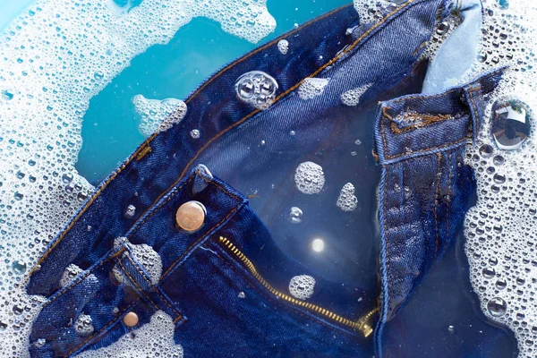 Jeans soak in powder detergent water dissolution. Laundry concep