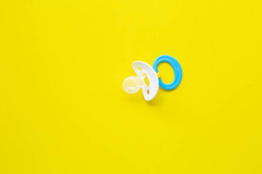 Sarı arka planda bebek emzik.