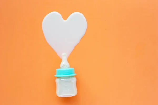 Flasche Milch für Baby auf orangefarbenem Hintergrund. — Stockfoto