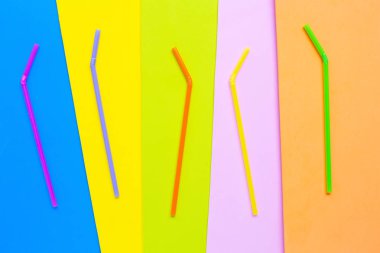 Renkli arka planda renkli plastik pipetler. 