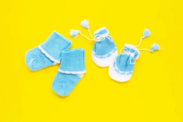 Baby-Handschuhe und Socken auf gelbem Hintergrund. — Stockfoto