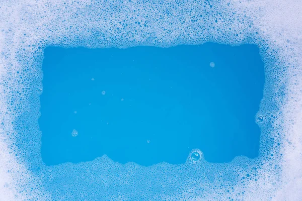 Rama wykonana z bańki piankowej detergentu. Niebieskie tło. — Zdjęcie stockowe