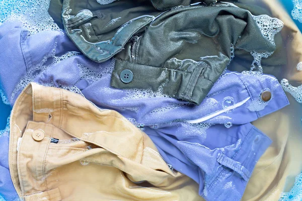 Los pantalones se sumergen en la disolución del agua del detergente en polvo. Servicio de lavandería con — Foto de Stock