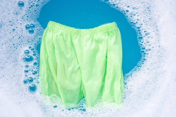 赤ちゃんの洗濯洗剤水のディゾルティに浸す緑の赤ちゃんのショートパンツ — ストック写真