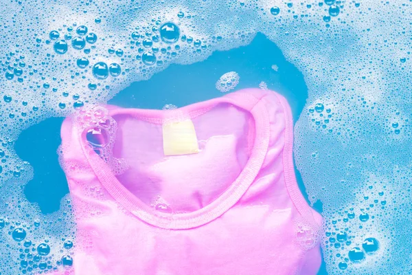 ピンクの子供のノースリーブシャツは、赤ちゃんの洗濯洗剤水dに浸す — ストック写真