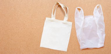 Kontrplak arka plan üzerinde beyaz plastik torba ile beyaz kumaş torba. 